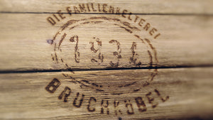 Rustikales Logo Familienkelterei Bruchköbel 1934 auf Holz